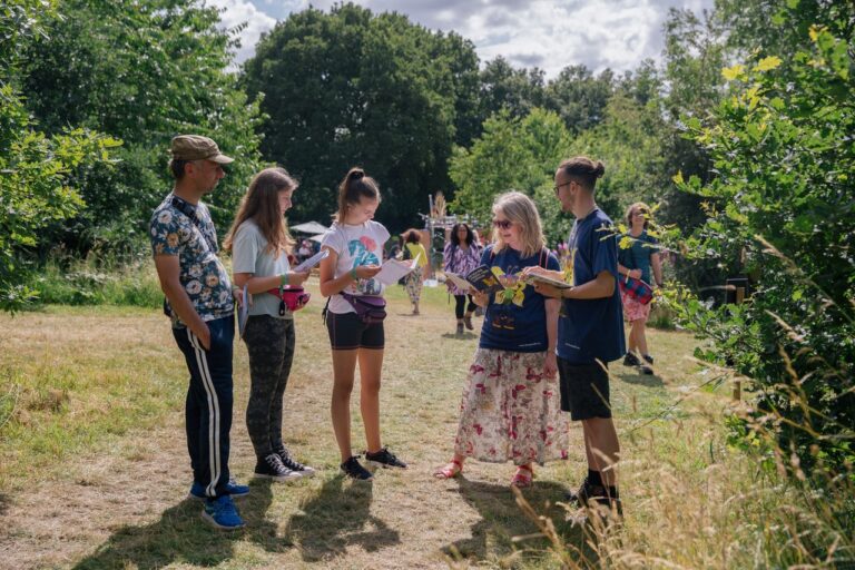 A photograph of past Writing East Midlands mentee and children's author Fiona Spence-Arnold reading her debut novel, Rhamni Finds Her Wings, with a group of young writers.